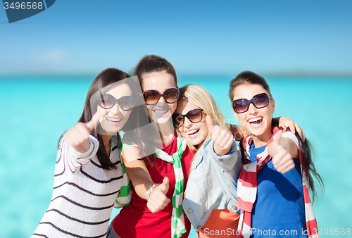 Image of happy teenage girls showing thumbs up on beach
