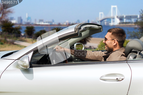 Image of happy man driving cabriolet car in tokyo