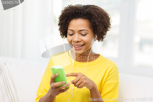 Image of happy african woman with smartphone and earphones