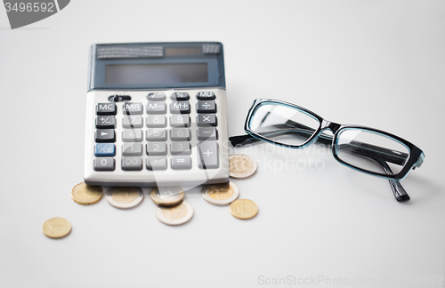 Image of calculator, glasses and euro coins on office table