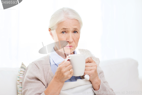 Image of sick senior woman drinking hot tea at home