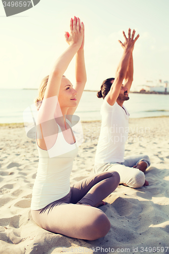 Image of smiling couple making yoga exercises outdoors