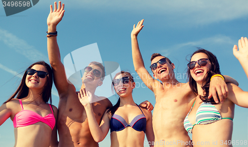 Image of smiling friends in sunglasses on summer beach