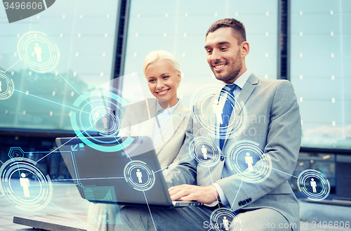 Image of smiling businesspeople with laptop outdoors