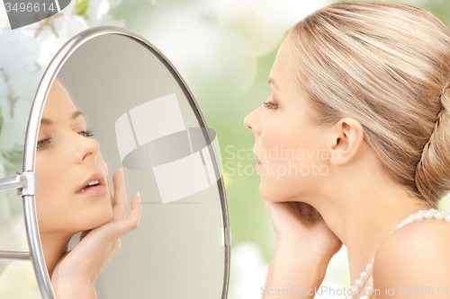 Image of beautiful woman with pearl necklace and mirror