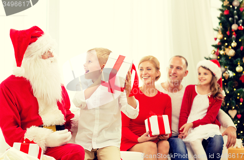 Image of smiling family with santa claus and gifts at home