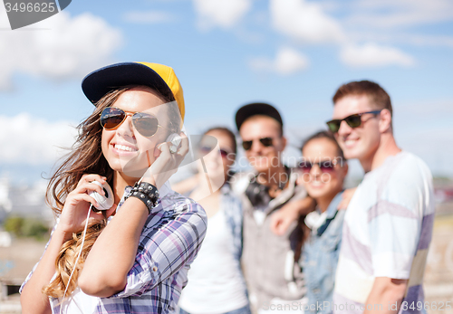 Image of teenage girl with headphones and friends outside