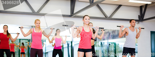 Image of group of smiling people working out with barbells