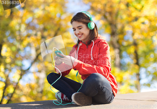 Image of happy young woman with smartphone and headphones