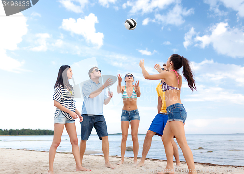 Image of group of happy friends playing beach ball