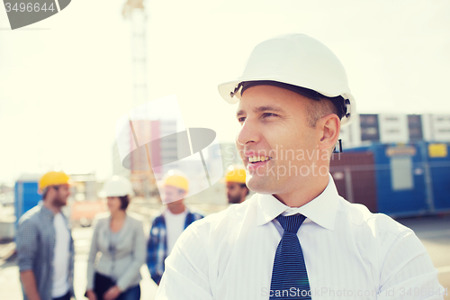 Image of group of smiling builders in hardhats outdoors