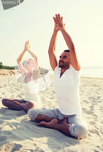 Image of smiling couple making yoga exercises outdoors