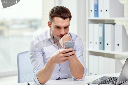 Image of businessman with smartphone and laptop at office