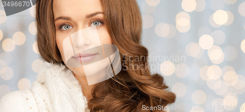 Image of smiling young woman in winter clothes over lights