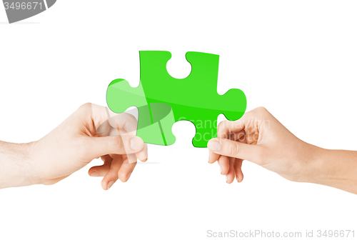 Image of close up of couple hands with green puzzle