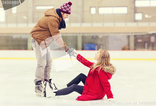 Image of man helping women to rise up on skating rink