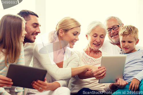 Image of smiling family with tablet pc at home