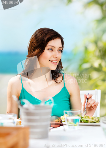 Image of girl eating in cafe on the beach
