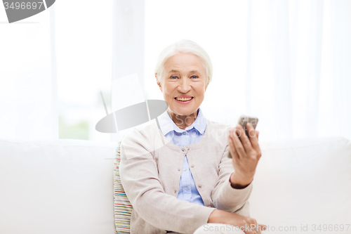 Image of senior woman with smartphone at home