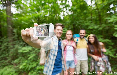 Image of friends with backpacks taking selfie by smartphone