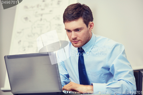 Image of businessman sitting with laptop in office