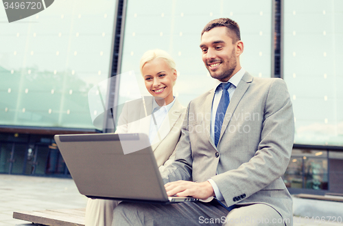 Image of smiling businesspeople with laptop outdoors