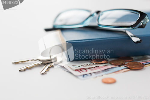 Image of close up of book, money, glasses and keys on table