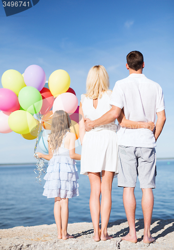 Image of happy family at the seaside with bunch of balloons