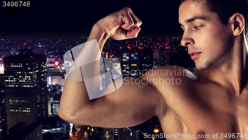 Image of close up of young man showing biceps