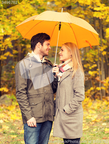 Image of smiling couple with umbrella in autumn park