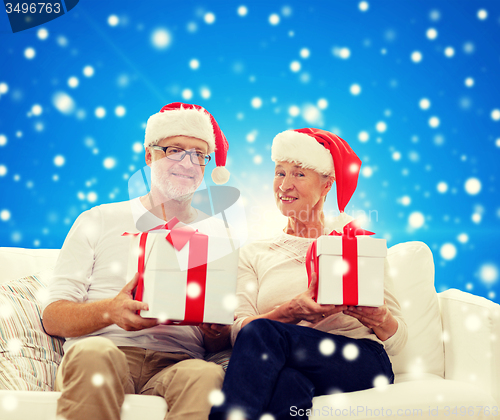 Image of happy senior couple in santa hats with gift boxes