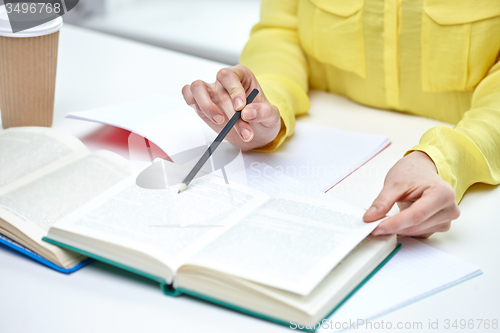 Image of close up of female hands with books and coffee