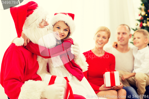 Image of smiling family with santa claus and gifts at home