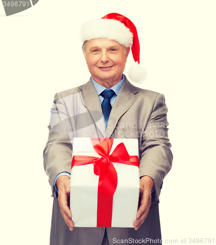 Image of smiling man in suit and santa helper hat with gift