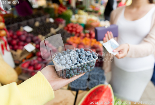 Image of pregnant woman with money buying berries at market