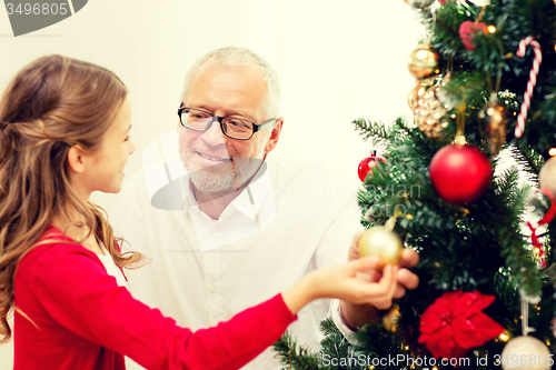 Image of smiling family decorating christmas tree at home