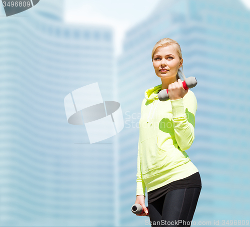 Image of sporty woman with light dumbbells outdoors