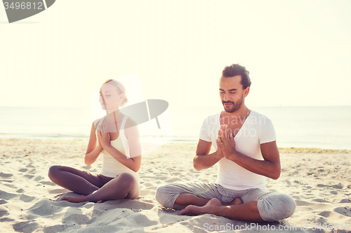 Image of smiling couple making yoga exercises outdoors