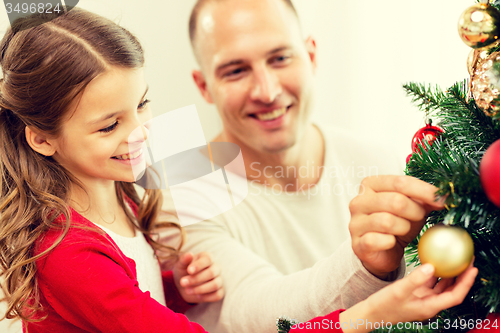 Image of smiling family decorating christmas tree at home