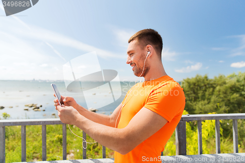 Image of smiling young man with smartphone and earphones