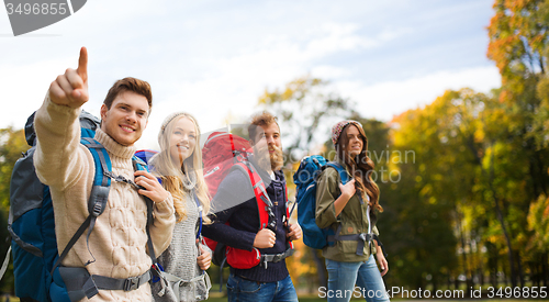 Image of smiling friends with backpacks hiking over nature