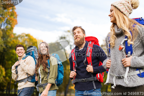 Image of smiling friends with backpacks hiking over nature