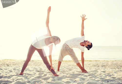 Image of couple making yoga exercises outdoors