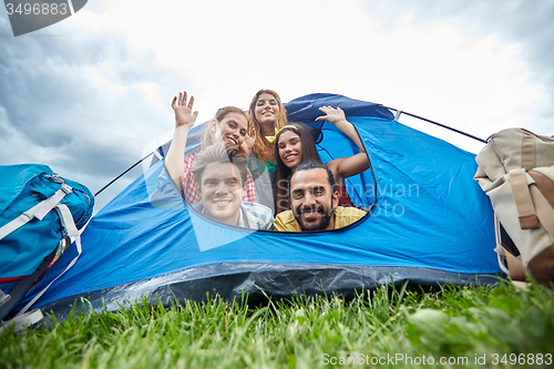 Image of happy friends with backpacks in tent at camping