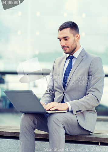 Image of businessman working with laptop outdoors