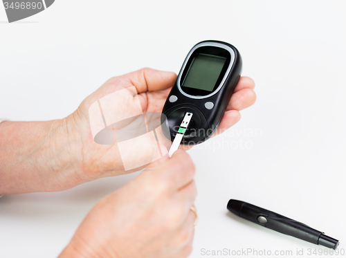 Image of senior woman with glucometer checking blood sugar