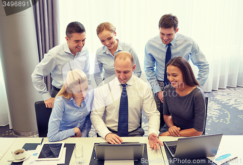 Image of smiling business people with laptop in office