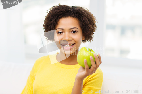 Image of happy african american woman with green apple