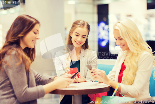 Image of happy women with smartphones and shopping bags