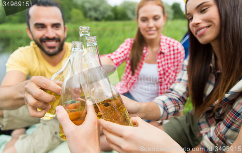 Image of happy friends with tent and drinks at campsite